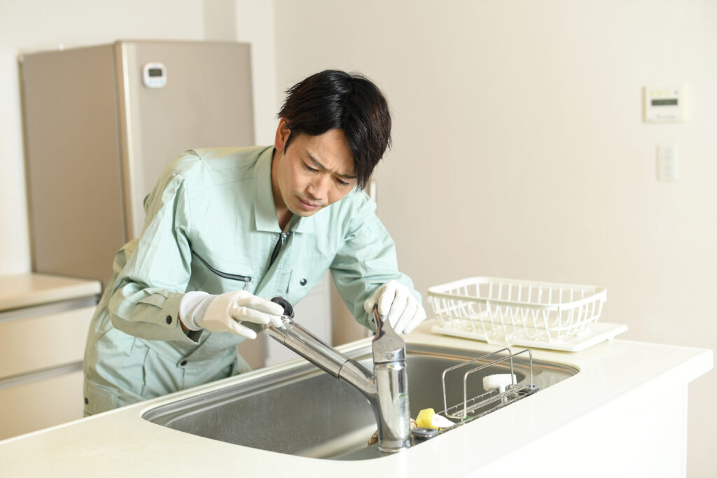 蛇口を修理する業者の男性